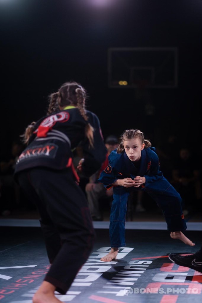 Miley in her blue gi facing an opponent at a jiu jitsu competition
